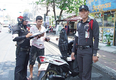 Lt. Purachet Rattanawichit (right) and 10 police officers set up random roadblocks to catch people violating traffic laws.